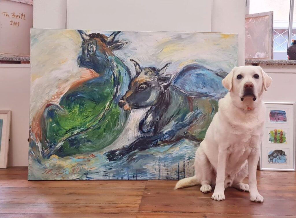 Bild von zwei liegenden Kühen in Blau-Grünen Farbtönen mit Hund Gustav, der freundlich davor sitzt