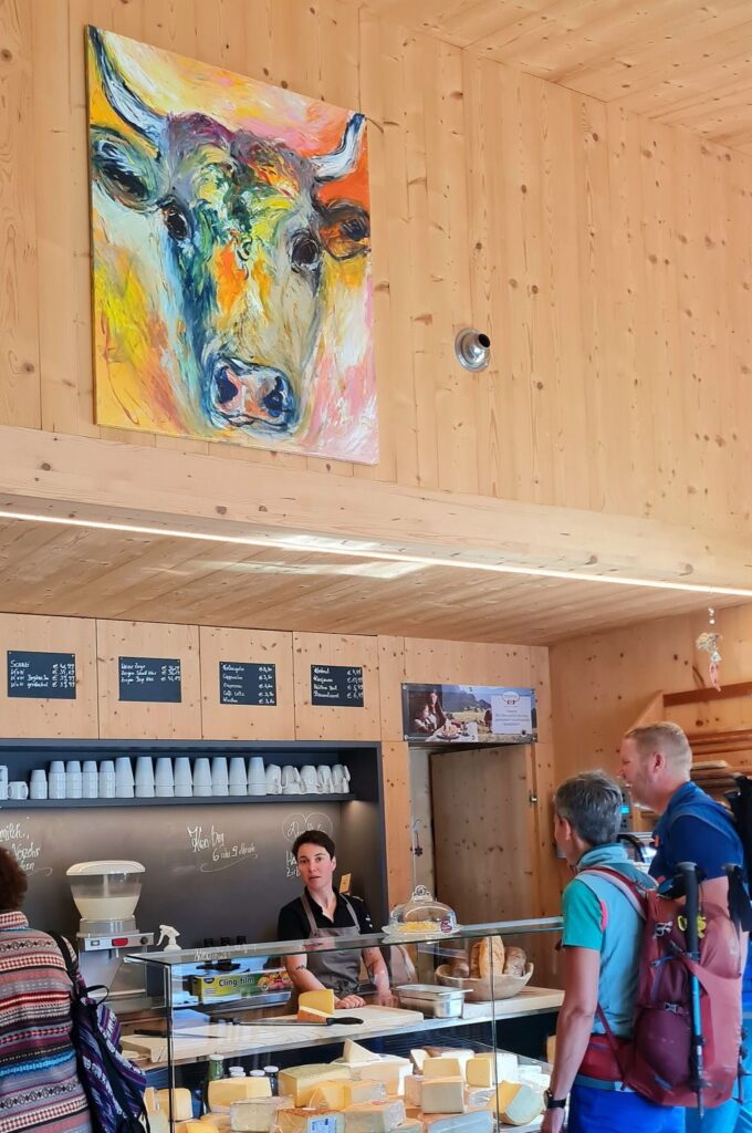 Blick in das Käsegeschäft KASLABN in Radenthein in Kärnten, mit Werk "Esmeralda" in Acrylmalerei von Theresa Beitl über der Theke